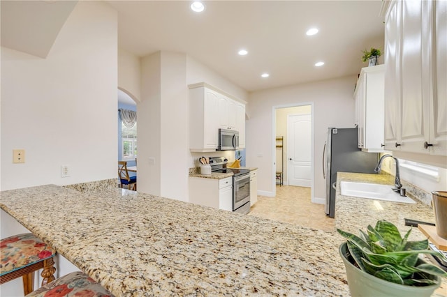 3145 Connemara Dr, Ormond Beach, FL 32174 - kitchen featuring stainless steel appliances, arched walkways, a sink, white cabinets, and recessed lighting
