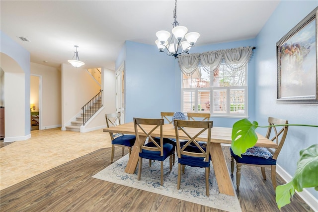 3145 Connemara Dr, Ormond Beach, FL 32174 - dining space with stairs, a chandelier, wood finished floors, and baseboards