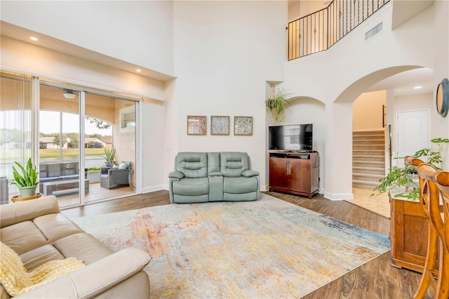 3145 Connemara Dr, Ormond Beach, FL 32174 - living room with a towering ceiling, baseboards, arched walkways, wood finished floors, and stairs