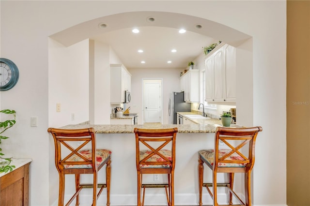 3145 Connemara Dr, Ormond Beach, FL 32174 - kitchen with a sink, appliances with stainless steel finishes, recessed lighting, light stone counters, and white cabinets
