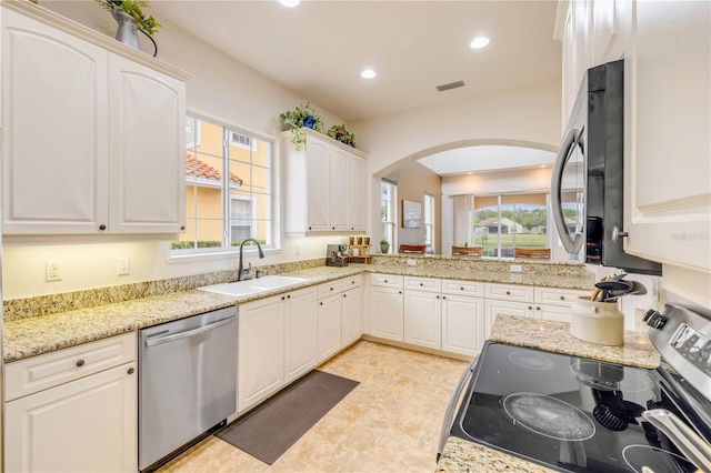 3145 Connemara Dr, Ormond Beach, FL 32174 - kitchen featuring stainless steel appliances, a sink, arched walkways, recessed lighting, and white cabinetry