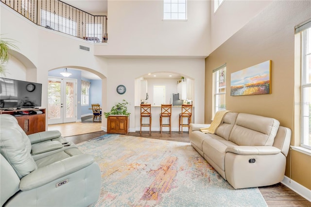 3145 Connemara Dr, Ormond Beach, FL 32174 - living room featuring arched walkways, wood finished floors, a towering ceiling, healthy amount of natural light, and baseboards