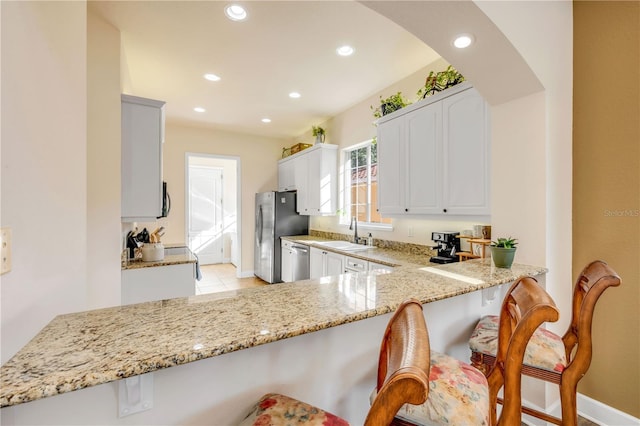 3145 Connemara Dr, Ormond Beach, FL 32174 - kitchen with appliances with stainless steel finishes, a breakfast bar area, light stone counters, and recessed lighting