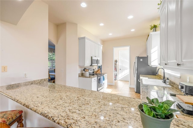 3145 Connemara Dr, Ormond Beach, FL 32174 - kitchen with stainless steel appliances, arched walkways, white cabinets, light stone countertops, and recessed lighting