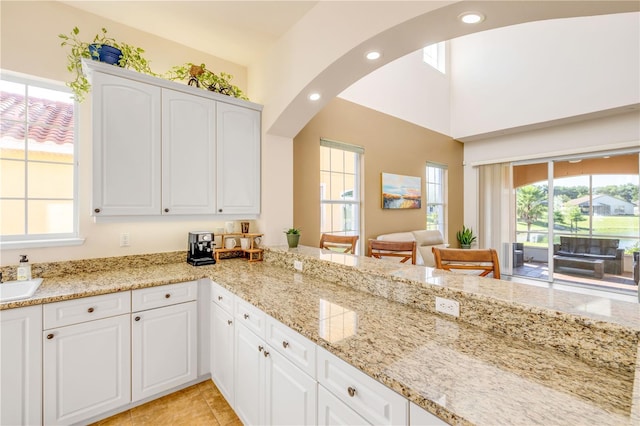3145 Connemara Dr, Ormond Beach, FL 32174 - kitchen with light stone counters, white cabinets, arched walkways, recessed lighting, and light tile patterned floors
