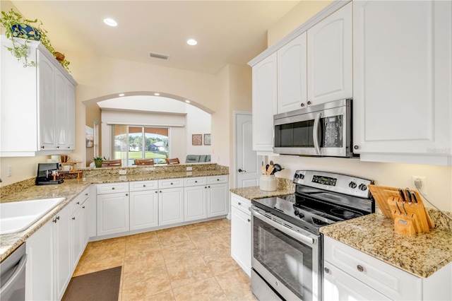 3145 Connemara Dr, Ormond Beach, FL 32174 - kitchen with appliances with stainless steel finishes, arched walkways, white cabinets, light stone countertops, and recessed lighting