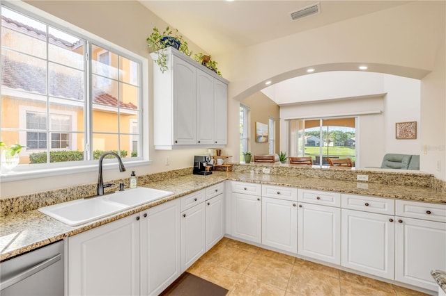 3145 Connemara Dr, Ormond Beach, FL 32174 - kitchen featuring dishwasher, arched walkways, recessed lighting, white cabinets, and light stone counters