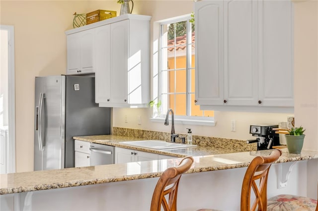 3145 Connemara Dr, Ormond Beach, FL 32174 - kitchen with stainless steel appliances, light stone counters, white cabinetry, and a kitchen bar