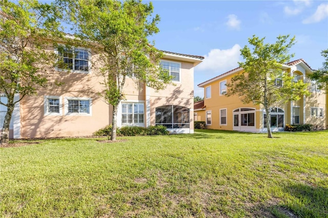 3145 Connemara Dr, Ormond Beach, FL 32174 - rear view of property featuring stucco siding, a lawn, and a sunroom