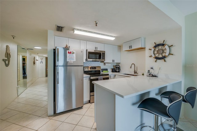 kitchen with visible vents, a sink, a peninsula, stainless steel appliances, and a breakfast bar area