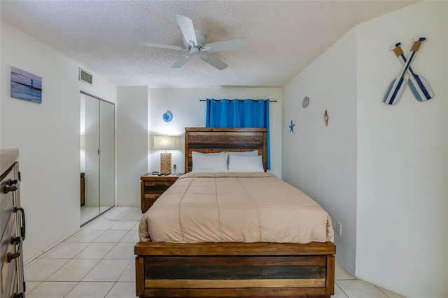 bedroom with light tile patterned floors, ceiling fan, a textured ceiling, a closet, and visible vents