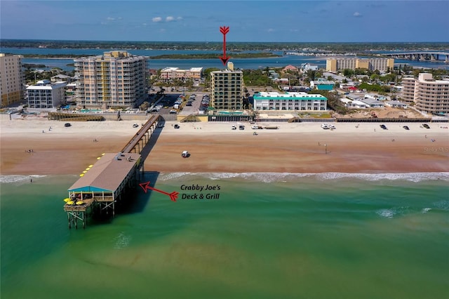 drone / aerial view with a water view, a city view, and a beach view