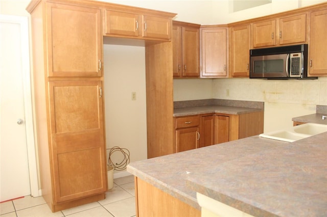 kitchen featuring light tile patterned flooring, stainless steel microwave, and backsplash