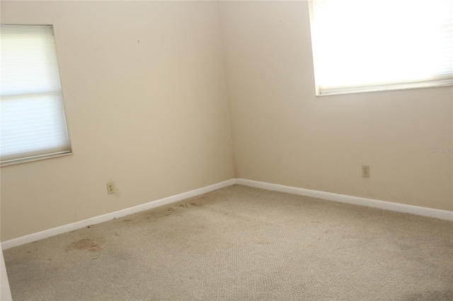 carpeted empty room featuring baseboards