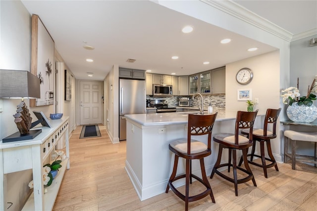 2967 S Atlantic Ave Unit 301, Daytona Beach Shores, FL 32118 - kitchen featuring stainless steel appliances, a peninsula, light wood-style flooring, glass insert cabinets, and a sink