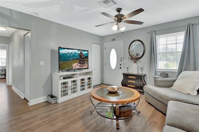 living room featuring baseboards, visible vents, wood finished floors, and ceiling fan