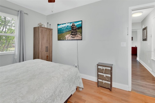 bedroom with a ceiling fan, baseboards, and light wood finished floors