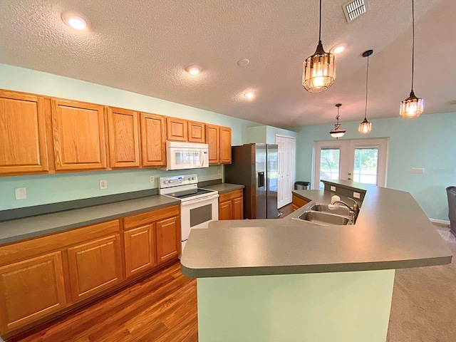 kitchen featuring visible vents, white appliances, a sink, a spacious island, and french doors