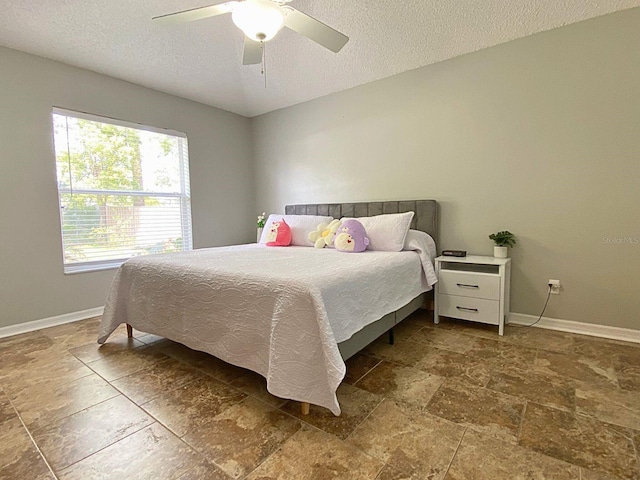 bedroom with baseboards, ceiling fan, and a textured ceiling