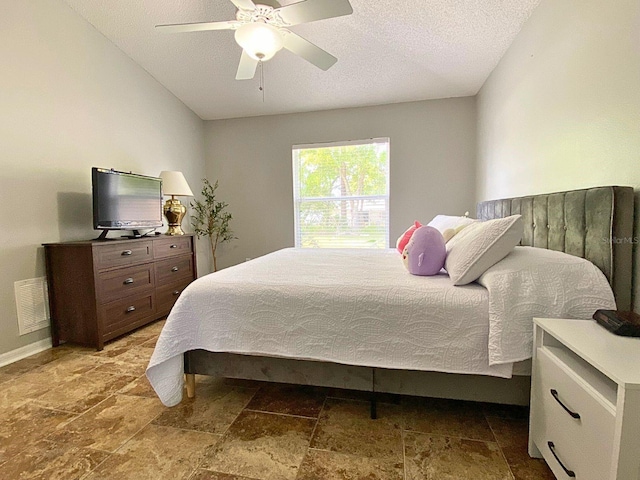 bedroom featuring stone finish floor, a textured ceiling, ceiling fan, and visible vents