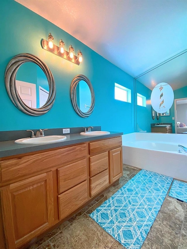 full bathroom with a bath, double vanity, and a sink