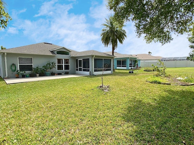 back of house with a sunroom, stucco siding, a patio, a shingled roof, and a lawn
