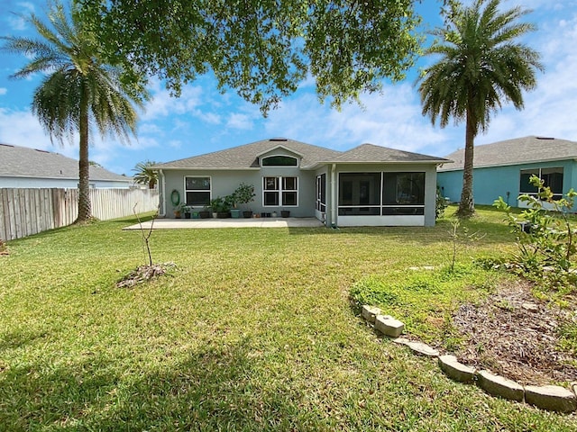 back of property with a sunroom, stucco siding, fence, a yard, and a patio area