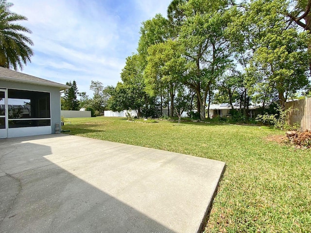 view of yard featuring a fenced backyard, a sunroom, and a patio area