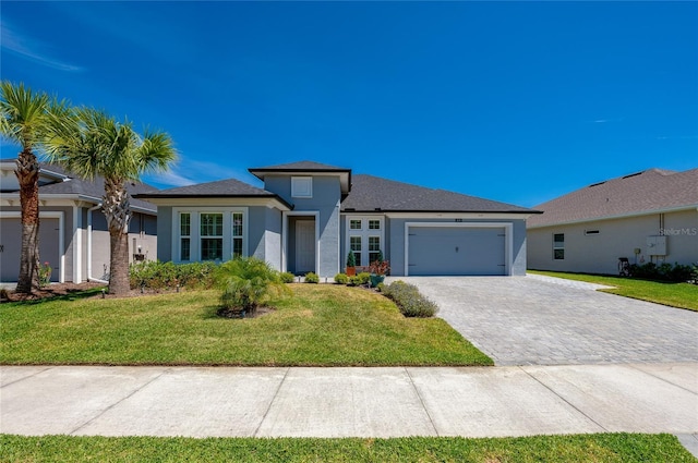 418 Aquamarine Way, Daytona Beach, FL 32124 - prairie-style house with stucco siding, a garage, a front lawn, and decorative driveway