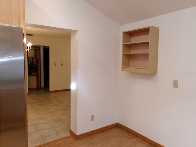 spare room with light wood-style floors, built in features, and baseboards