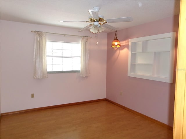 empty room featuring baseboards, wood finished floors, and a ceiling fan