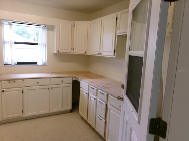 kitchen with white cabinetry, light countertops, and light colored carpet