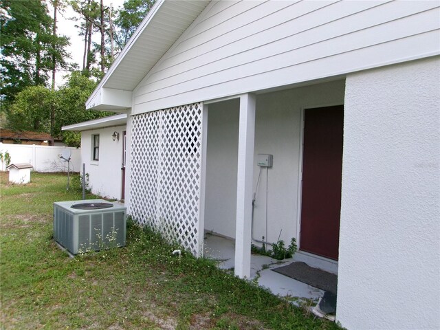 view of home's exterior featuring stucco siding, central AC unit, and a lawn