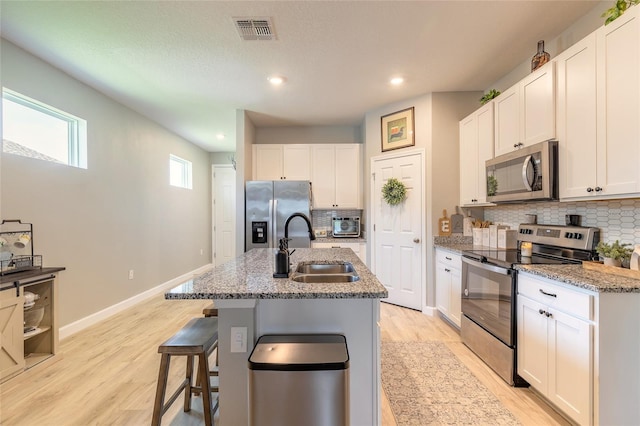 3128 Crab Trap Dr, New Smyrna Beach, FL 32168 - kitchen featuring appliances with stainless steel finishes, a sink, backsplash, light wood-style floors, and white cabinets