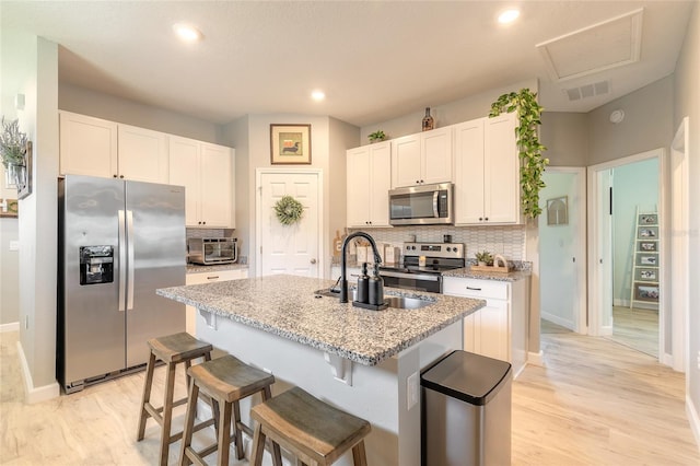 3128 Crab Trap Dr, New Smyrna Beach, FL 32168 - kitchen with stainless steel appliances, tasteful backsplash, white cabinets, light wood finished floors, and recessed lighting