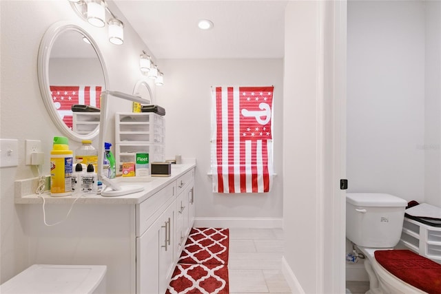 bathroom with toilet, vanity, baseboards, and recessed lighting