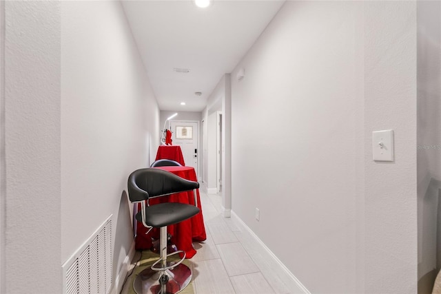 hallway with baseboards and visible vents