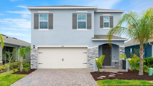3120 Areca Ave, New Smyrna Beach, FL 32168 - view of front facade featuring stucco siding, decorative driveway, stone siding, an attached garage, and a shingled roof