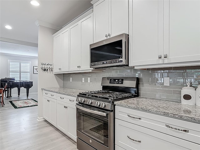 425 Wedgeworth Ln, Deland, FL 32724 - kitchen featuring white cabinetry, stainless steel appliances, decorative backsplash, light wood-style floors, and light stone counters