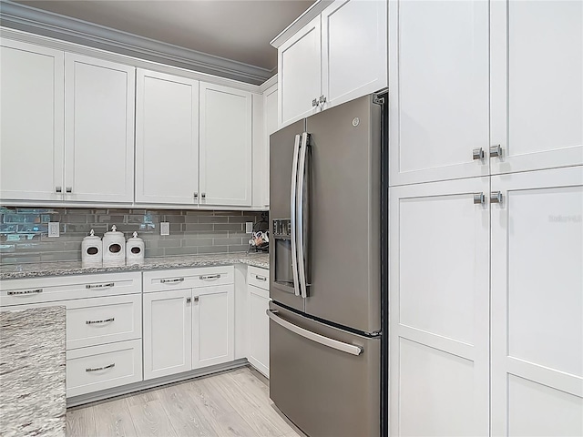 425 Wedgeworth Ln, Deland, FL 32724 - kitchen with light stone counters, white cabinetry, stainless steel fridge, light wood-style flooring, and decorative backsplash