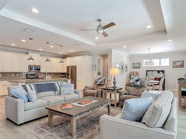 425 Wedgeworth Ln, Deland, FL 32724 - living room with ornamental molding, light wood-style floors, ceiling fan with notable chandelier, and a raised ceiling