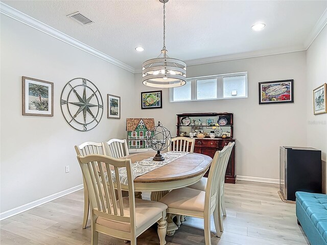 425 Wedgeworth Ln, Deland, FL 32724 - dining area with visible vents, crown molding, light wood-style floors, and an inviting chandelier