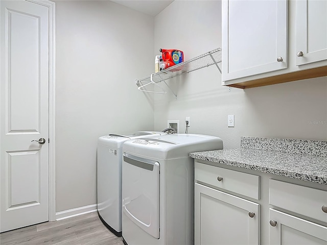 425 Wedgeworth Ln, Deland, FL 32724 - laundry area featuring baseboards, light wood-type flooring, washer and dryer, and cabinet space