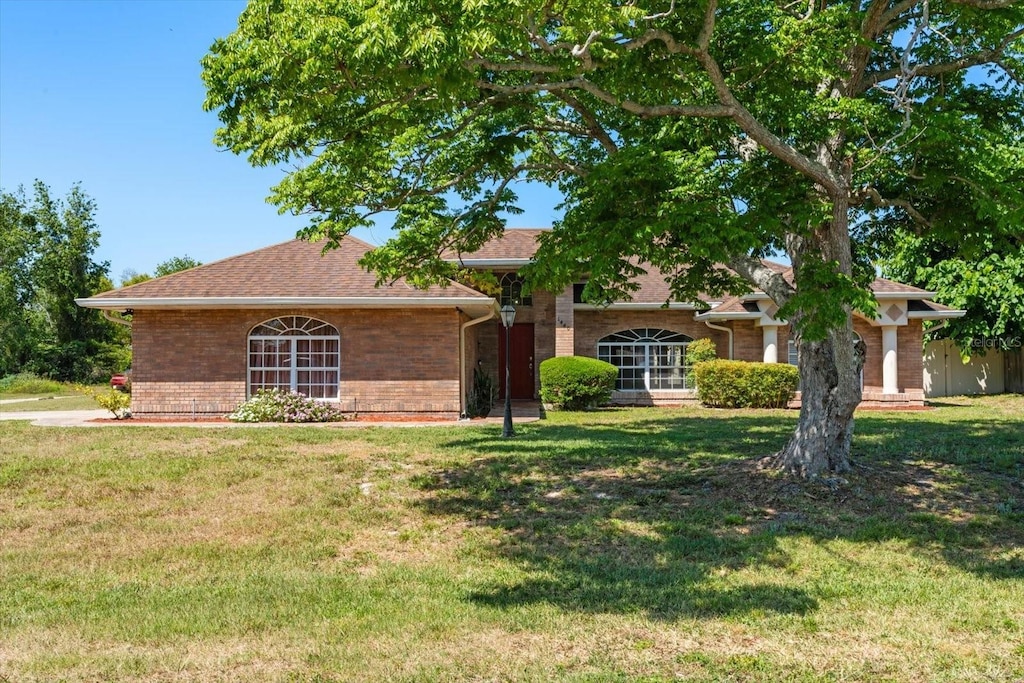 1440 Portola Ave, Deltona, FL 32738 - view of front of house featuring brick siding, a front lawn, and roof with shingles