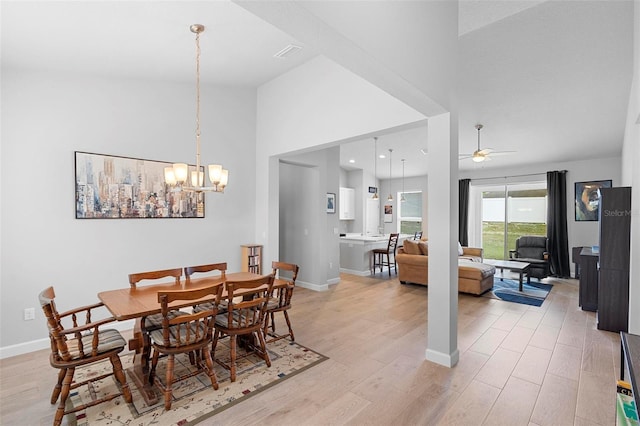 1601 Toledo Ave, Deltona, FL 32725 - dining area featuring baseboards, light wood finished floors, high vaulted ceiling, and ceiling fan with notable chandelier