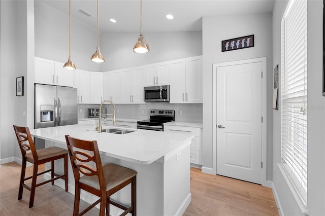 1601 Toledo Ave, Deltona, FL 32725 - kitchen with a kitchen island with sink, a sink, hanging light fixtures, stainless steel appliances, and a breakfast bar area