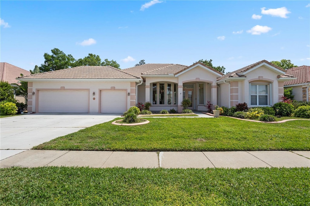 6111 Oxbow Bend Ln, Port Orange, FL 32128 - mediterranean / spanish-style house featuring stucco siding, driveway, an attached garage, a front yard, and a tiled roof