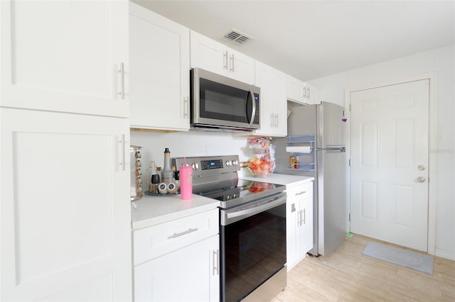 5261 3rd St, Orlando, FL 32810 - kitchen featuring light countertops, visible vents, white cabinets, stainless steel appliances, and light wood-type flooring