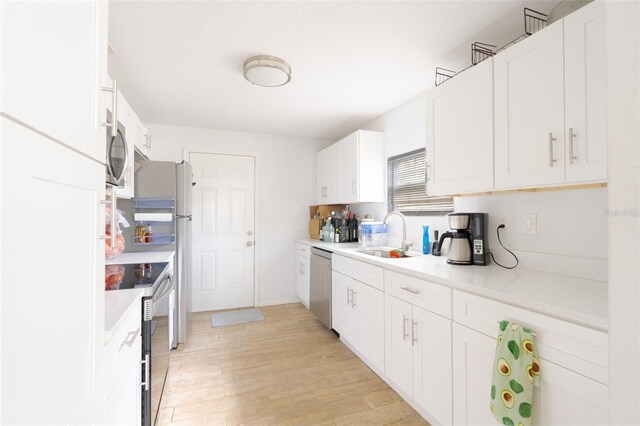 5261 3rd St, Orlando, FL 32810 - kitchen with light countertops, light wood-style flooring, stainless steel appliances, white cabinetry, and a sink
