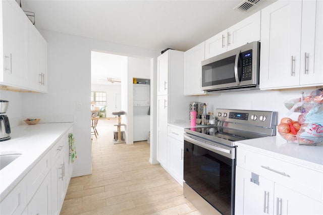 5261 3rd St, Orlando, FL 32810 - kitchen with light countertops, appliances with stainless steel finishes, light wood-type flooring, visible vents, and white cabinets